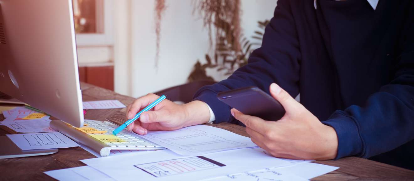 A man is using a cell phone while sitting at a desk.