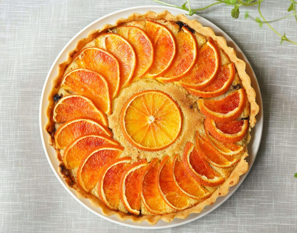 A baked orange pie with orange slices resting on top.
