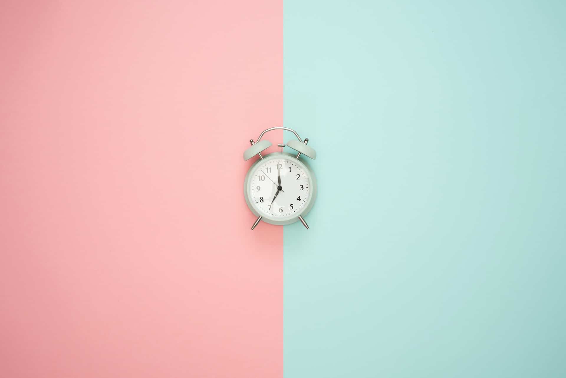 An alarm clock on a pink and blue background An alarm clock on a pink and blue background.